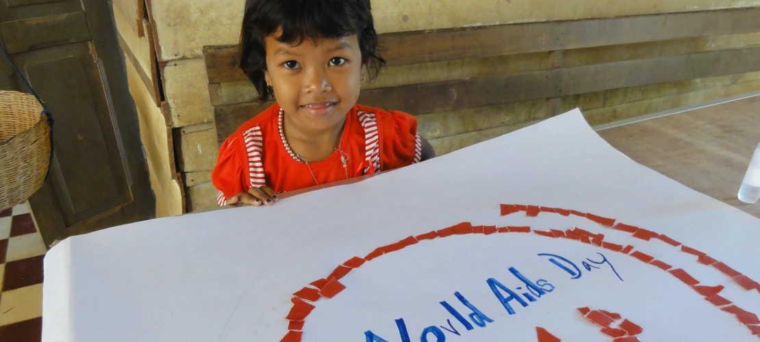 Young girl holding poster with HIV/Aids ribbon, World Aids Day 2011, Cambodia, PC Digital Library